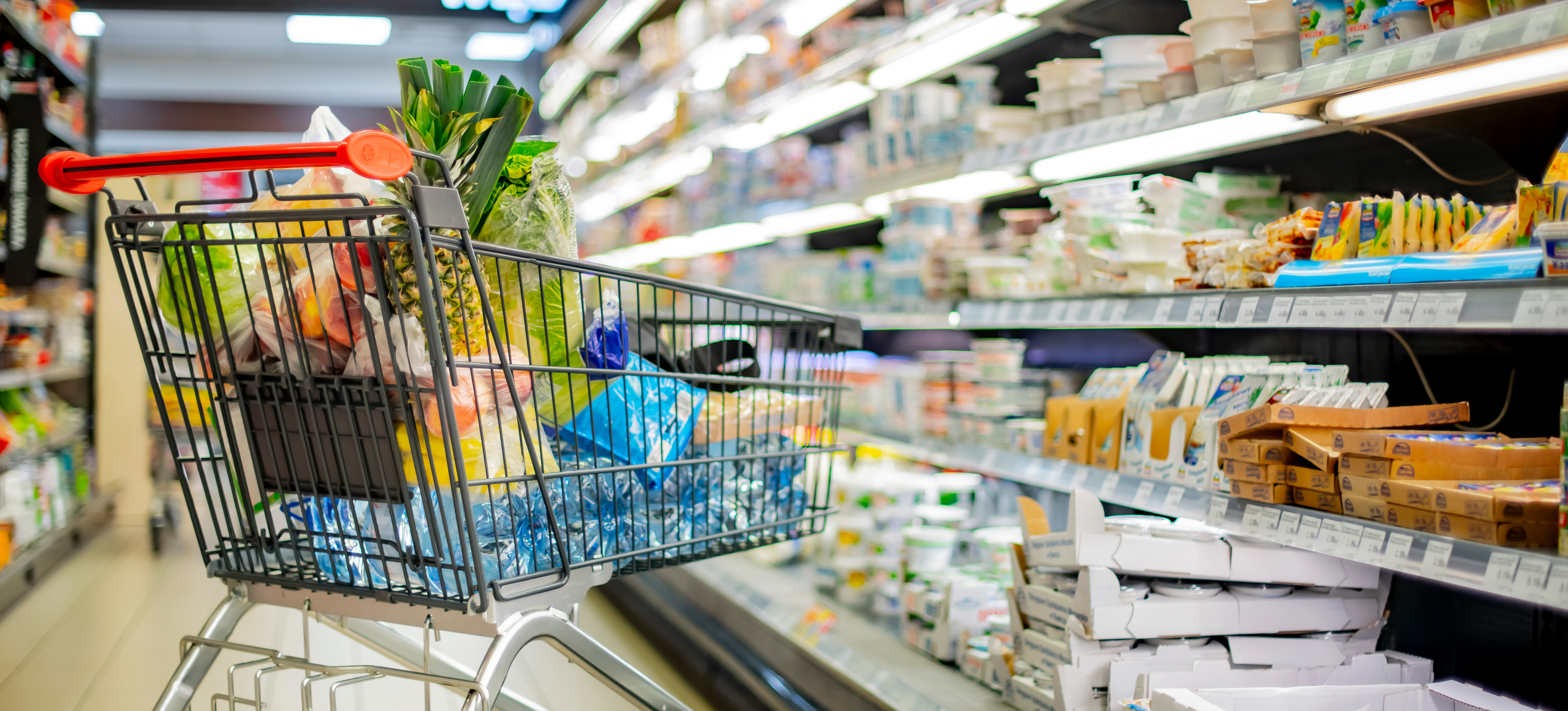 A shopping cart with grocery products in a supermarket
